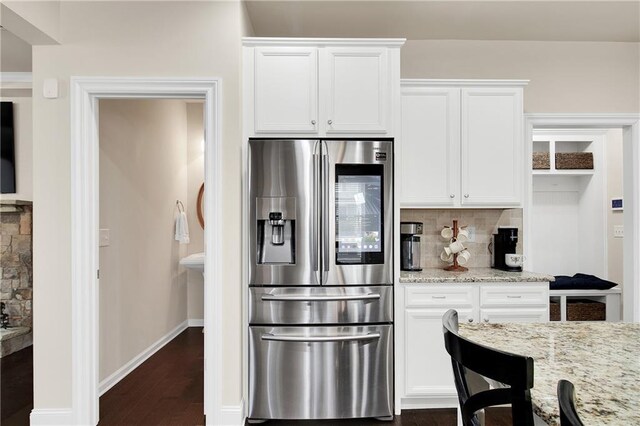 kitchen featuring dark wood-type flooring, white cabinetry, backsplash, light stone counters, and stainless steel fridge with ice dispenser