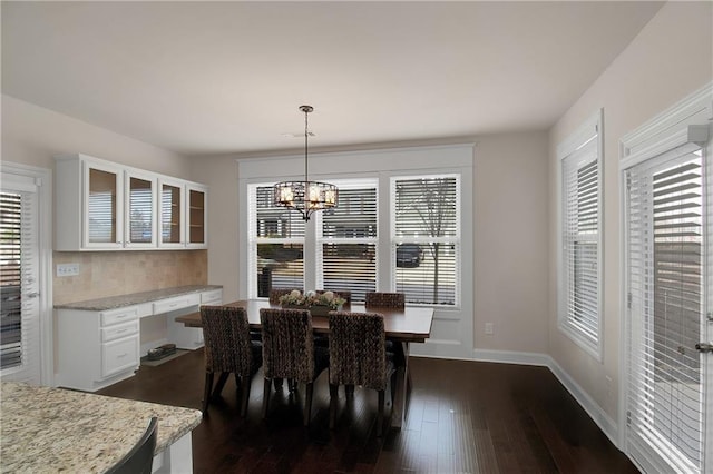 dining area with dark wood-type flooring, built in desk, and a notable chandelier