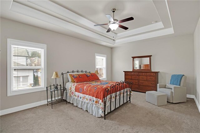 carpeted bedroom featuring a raised ceiling and ceiling fan