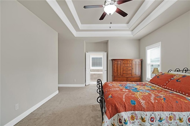 carpeted bedroom with a raised ceiling, ensuite bathroom, and ceiling fan