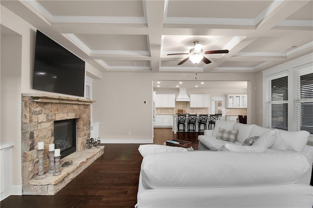 living room featuring a fireplace, beamed ceiling, coffered ceiling, ceiling fan, and dark wood-type flooring