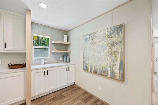 kitchen featuring decorative backsplash, white cabinets, and light wood-type flooring