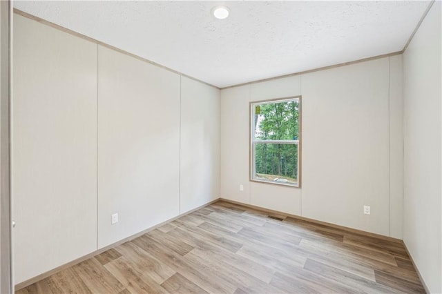 unfurnished room with crown molding, light hardwood / wood-style floors, and a textured ceiling