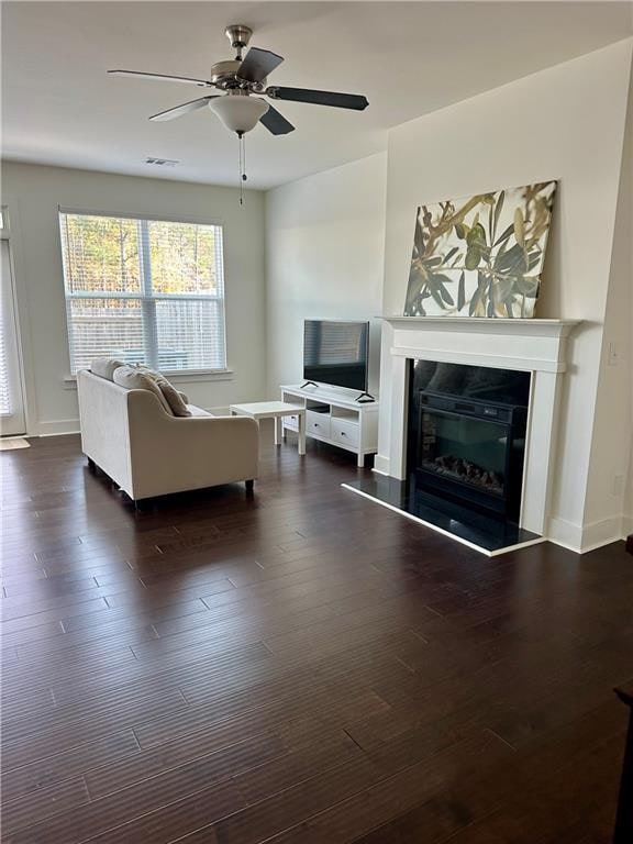 unfurnished living room with dark hardwood / wood-style flooring and ceiling fan