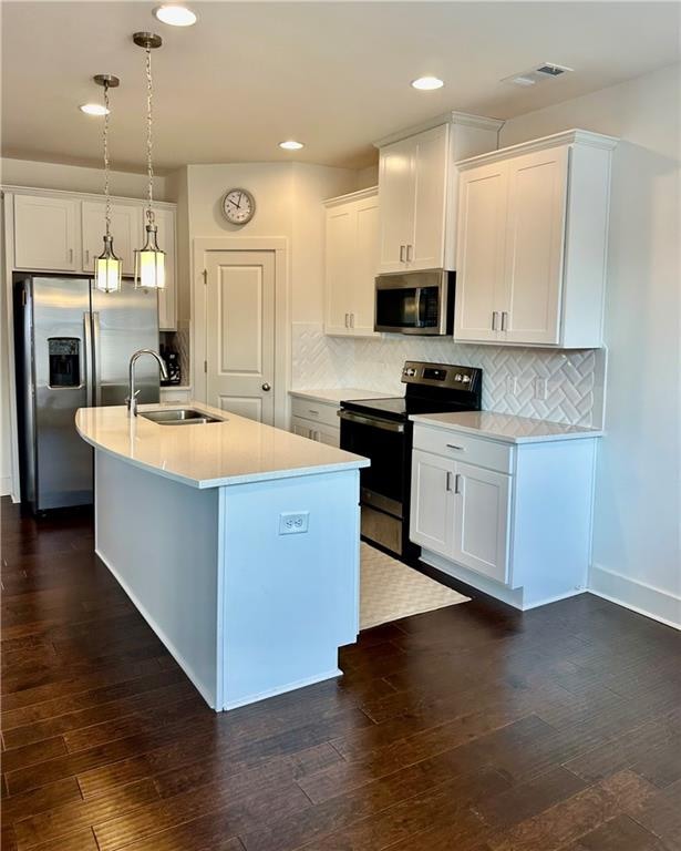 kitchen featuring appliances with stainless steel finishes, sink, a center island with sink, decorative light fixtures, and white cabinets