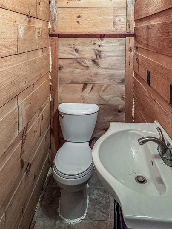 bathroom featuring sink, wooden walls, and toilet