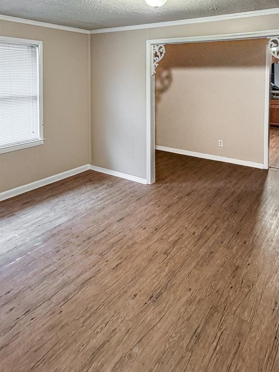 empty room featuring wood-type flooring, a textured ceiling, and crown molding