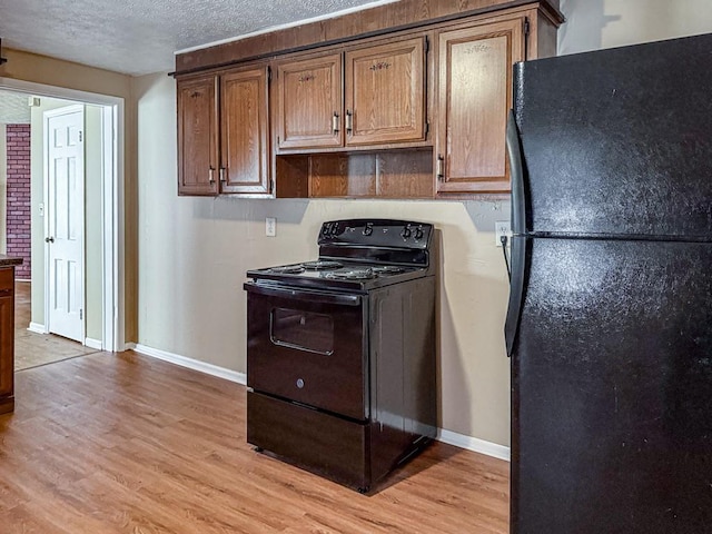 kitchen with black appliances, light hardwood / wood-style floors, and a textured ceiling