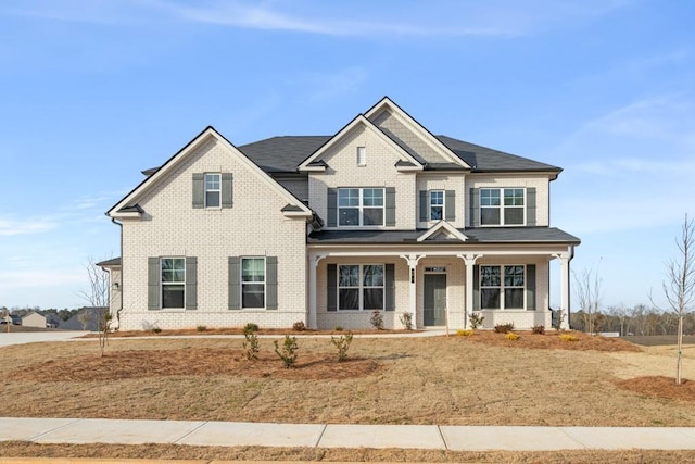 craftsman inspired home with covered porch, a front lawn, and brick siding