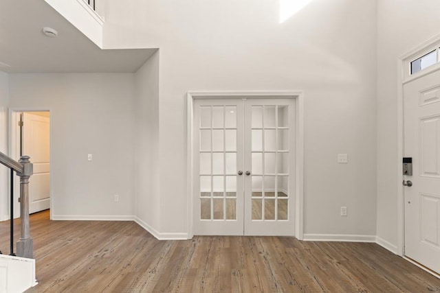 foyer featuring stairway, baseboards, wood finished floors, and french doors