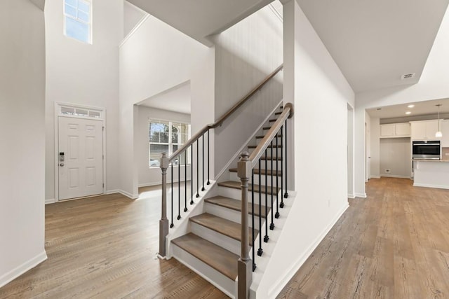 stairway featuring recessed lighting, wood finished floors, visible vents, and baseboards