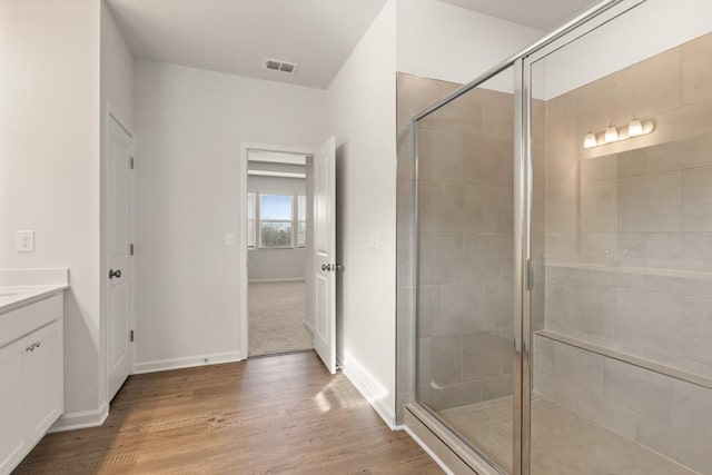 full bathroom featuring a stall shower, visible vents, vanity, and wood finished floors