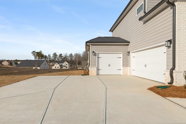 view of side of home featuring a residential view, brick siding, and driveway