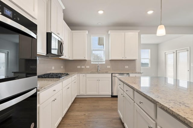 kitchen featuring stainless steel appliances, white cabinetry, hanging light fixtures, and a sink