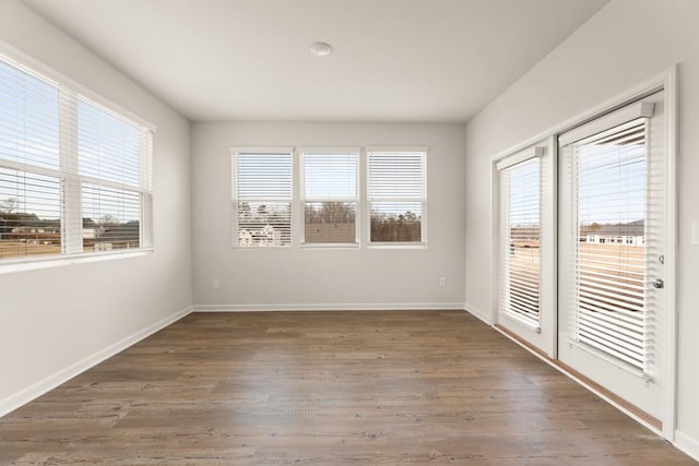 spare room with dark wood-type flooring and baseboards