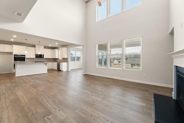 unfurnished living room with plenty of natural light, visible vents, a fireplace, and wood finished floors