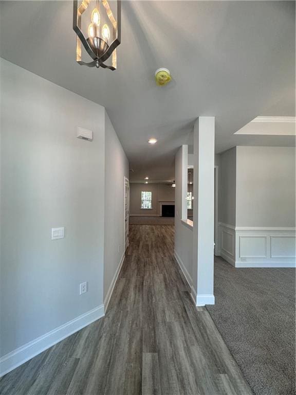 corridor with dark wood-type flooring and an inviting chandelier