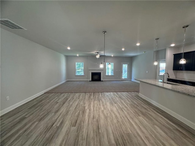 unfurnished living room featuring hardwood / wood-style floors, ceiling fan, and sink