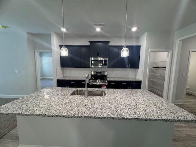 kitchen featuring hanging light fixtures, sink, an island with sink, and appliances with stainless steel finishes