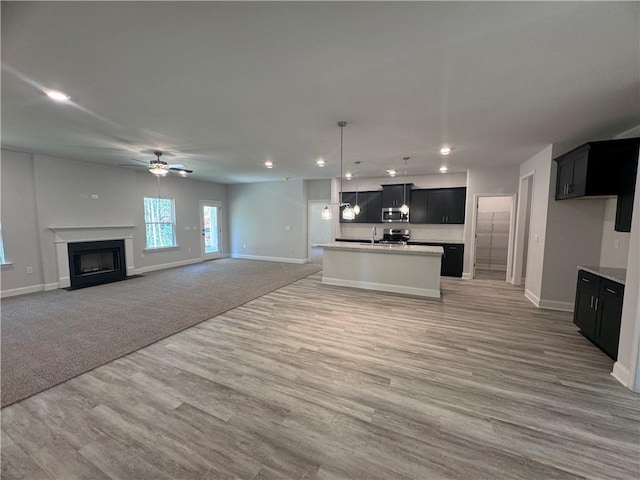 unfurnished living room with hardwood / wood-style floors, ceiling fan, and sink