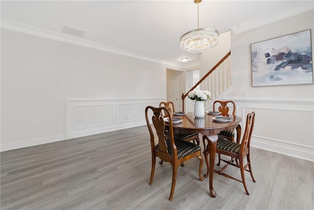 6018 Oakdale Rd SE, Mableton, GA 30126 - dining room with a decorative wall, stairway, light wood-style floors, a chandelier, and crown molding