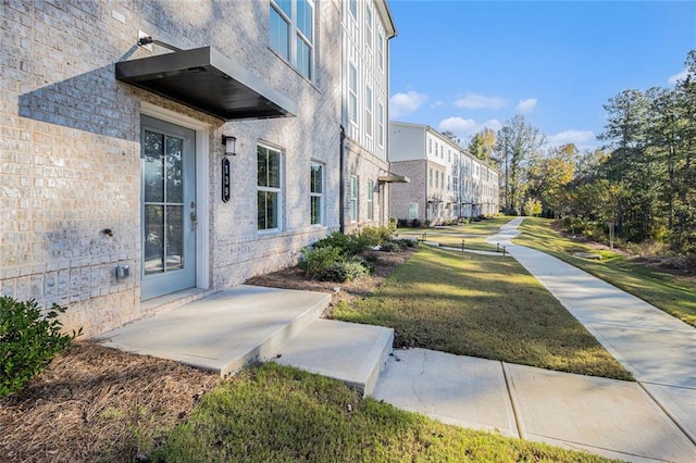 exterior space featuring brick siding and a yard