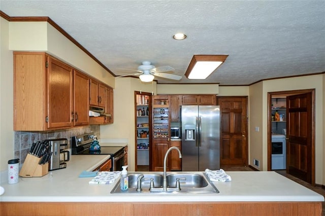 118 Heritage Way, Peachtree City, GA 30269 - kitchen with appliances with stainless steel finishes, under cabinet range hood, washer / dryer, light countertops, and a peninsula