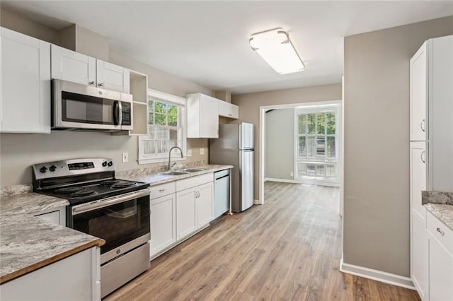 kitchen featuring baseboards, light wood-style floors, white cabinets, and stainless steel appliances