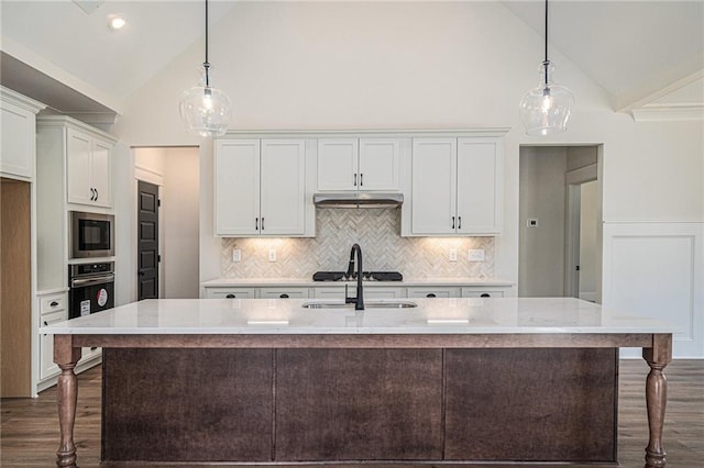 kitchen featuring a kitchen island with sink, decorative light fixtures, light stone countertops, and white cabinets