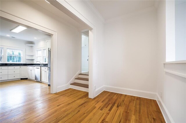 hallway featuring light hardwood / wood-style flooring, ornamental molding, and sink