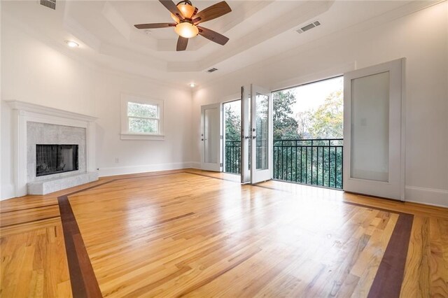 unfurnished living room featuring ceiling fan, wood-type flooring, and a tray ceiling