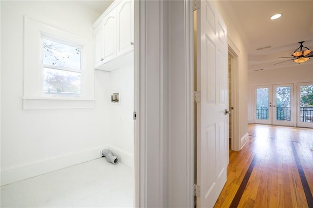 hall featuring a healthy amount of sunlight, light hardwood / wood-style flooring, and french doors