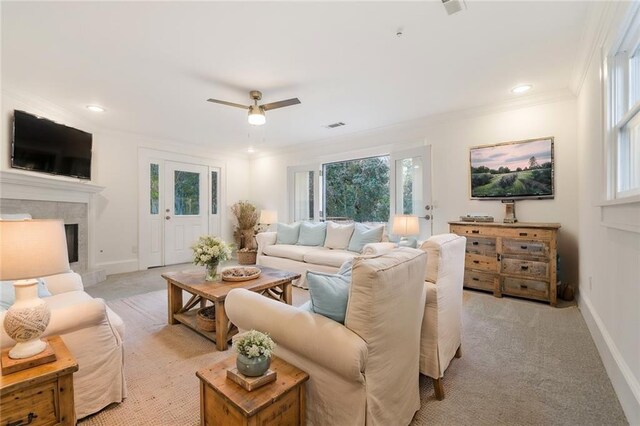 carpeted living room featuring a tile fireplace, ceiling fan, and crown molding