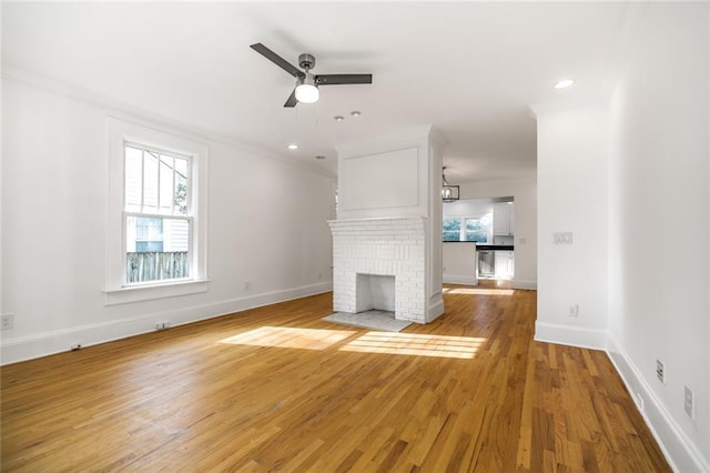 unfurnished living room featuring ceiling fan, light hardwood / wood-style floors, and a brick fireplace