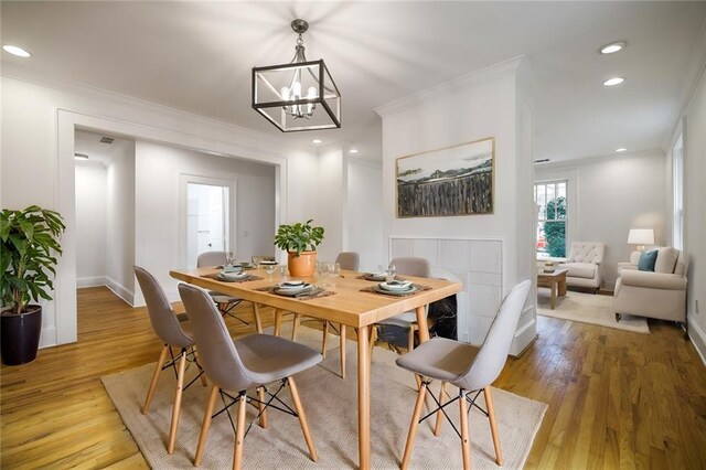 dining room with light hardwood / wood-style floors, crown molding, and a notable chandelier