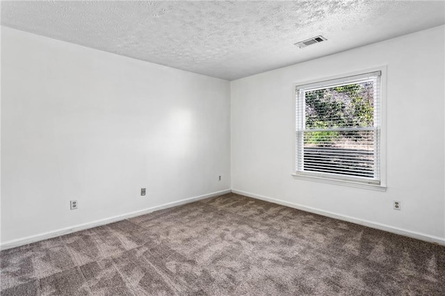 carpeted spare room featuring visible vents, baseboards, and a textured ceiling