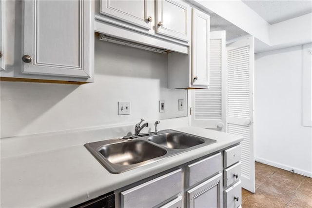 kitchen featuring a sink, baseboards, light tile patterned flooring, and light countertops