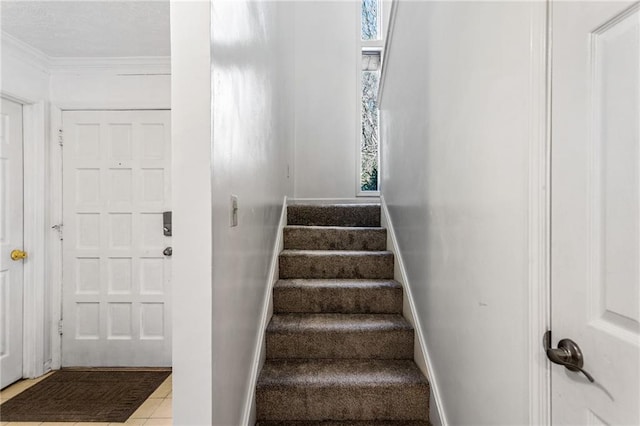 stairway with tile patterned flooring, crown molding, and baseboards