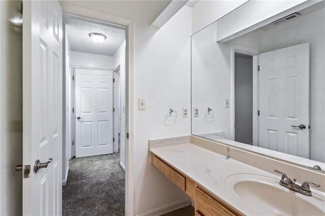 bathroom with vanity, baseboards, visible vents, and a textured ceiling