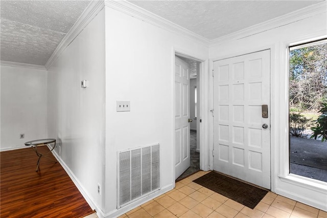 entryway featuring visible vents, baseboards, a textured ceiling, and crown molding