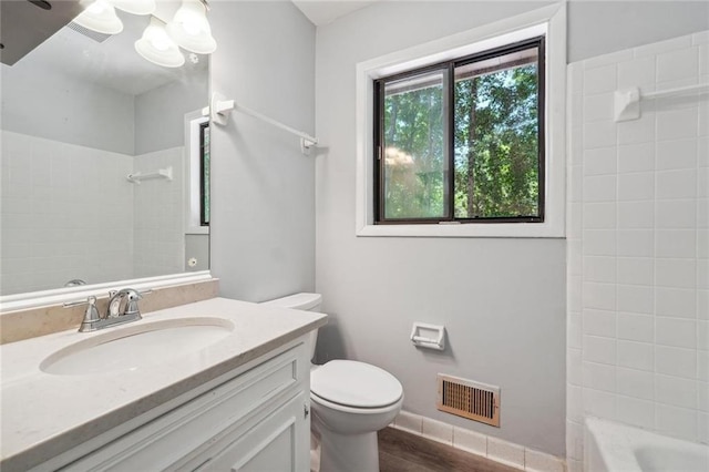 full bathroom featuring tiled shower / bath, toilet, vanity, and hardwood / wood-style flooring