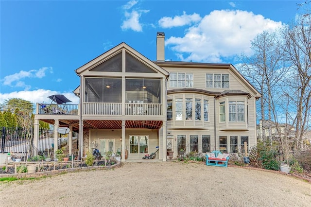 back of property featuring fence, a chimney, and a sunroom