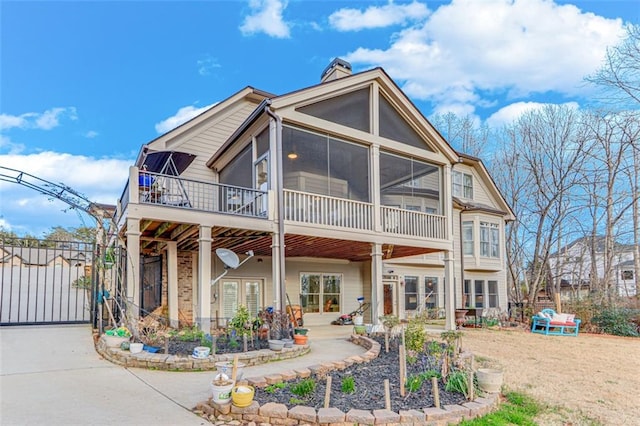 rear view of house featuring a chimney, a gate, french doors, a patio area, and a sunroom