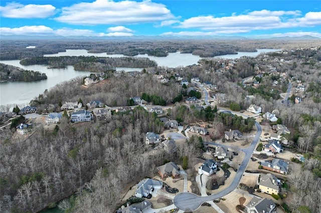 drone / aerial view featuring a wooded view, a residential view, and a water view