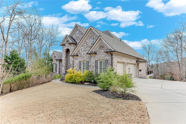 french country style house featuring a garage, driveway, and brick siding