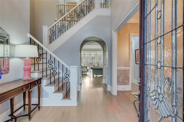 entryway with stairway, a high ceiling, wood finished floors, arched walkways, and baseboards