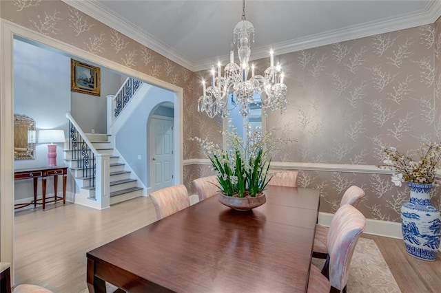 dining room featuring a chandelier, wallpapered walls, wood finished floors, and arched walkways