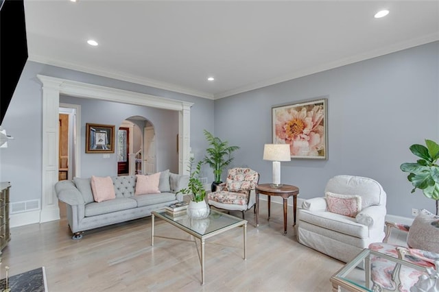 living room featuring crown molding, light wood-style floors, arched walkways, visible vents, and recessed lighting