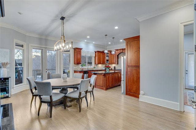 dining area with light wood-type flooring, an inviting chandelier, ornamental molding, and a healthy amount of sunlight