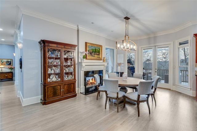 dining area featuring light wood-type flooring, ornamental molding, an inviting chandelier, and a multi sided fireplace